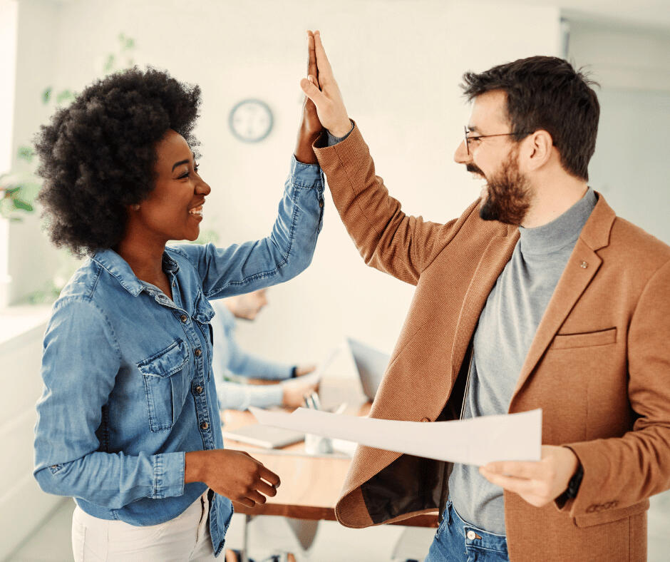Two business professionals high-fiving over a successful marketing project.