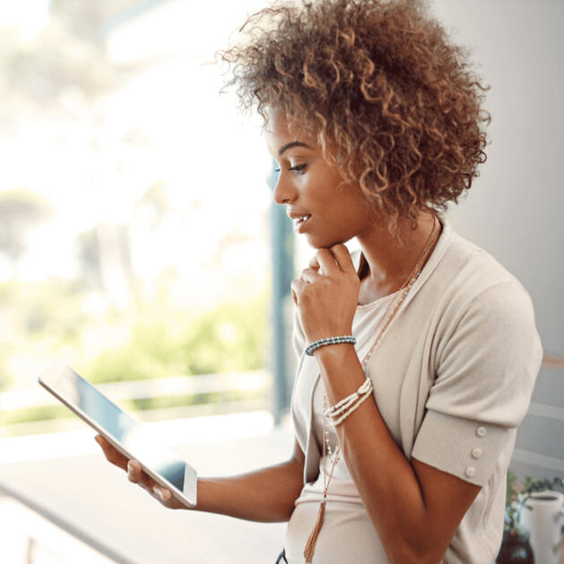 woman looking at tablet touching chin in thought